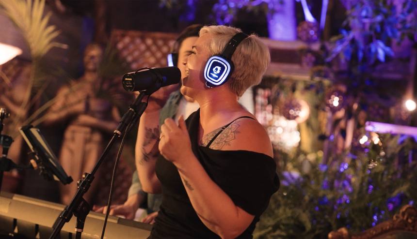 Vocalist singing into a microphone wearing glowing blue headphones